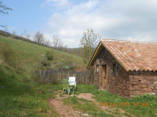 a stone house with two chairs and a building at Gîte des Monts in Saint-Izaire