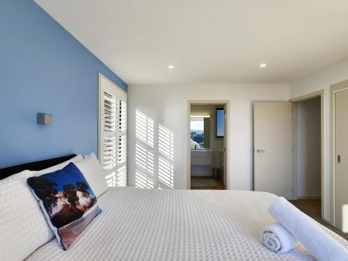 a bedroom with a white bed with a blue wall at The Barn Hot Water Beach in Hotwater Beach