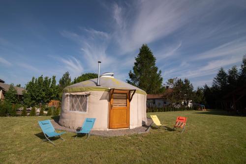 a yurt in a field with two chairs and chairs at Jurty Mongolskie Susiec in Susiec
