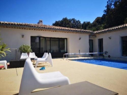 une terrasse avec des chaises blanches et une piscine dans l'établissement Le riva, à Mollans-sur-Ouvèze