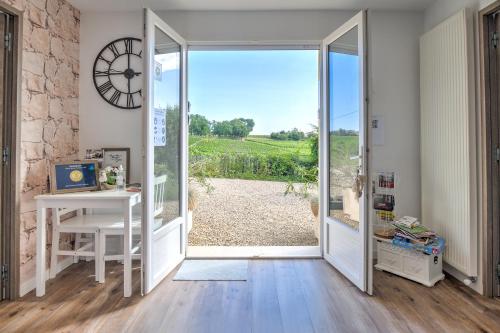 une porte ouverte menant à une chambre dotée d'un bureau et d'une fenêtre. dans l'établissement Au Charmant Des Vignes, à Montagne