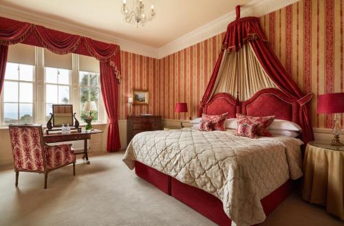 a bedroom with a red canopy bed and a desk at Glenapp Castle in Ballantrae