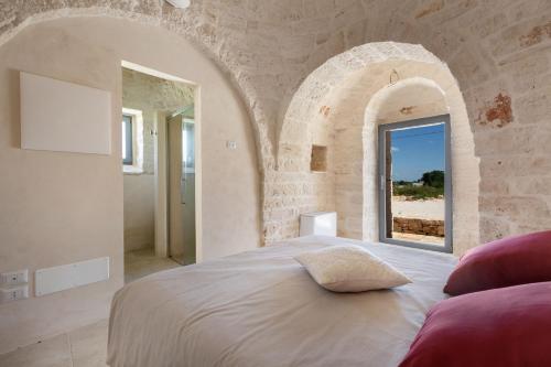 Un dormitorio con una cama grande en una pared de piedra. en Brunaldi Trulli by Perle di Puglia, en Martina Franca