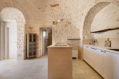 cocina grande con pared de piedra en Brunaldi Trulli by Perle di Puglia, en Martina Franca