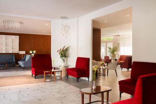 a waiting room with red chairs and tables at Hotel American Palace Eur in Rome