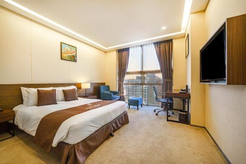 a hotel room with a bed and a flat screen tv at Gloucester Hotel Incheon in Incheon