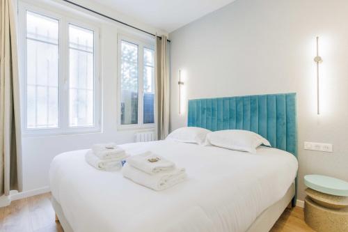 une chambre avec un grand lit blanc avec des serviettes dessus dans l'établissement Cozy Apartment 2BR-6P - Sacré-Coeur - Montmartre, à Paris