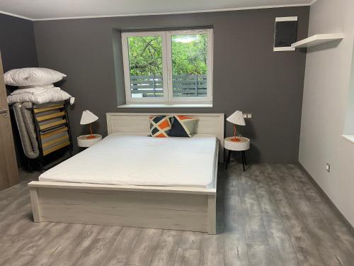 a bedroom with a bed and two tables with lamps at Karát Apartmanok in Gyula