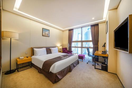 a hotel room with a bed and a flat screen tv at Gloucester Hotel Incheon in Incheon