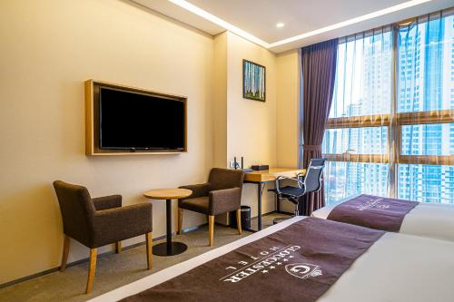 a hotel room with a bed and a desk and a tv at Gloucester Hotel Incheon in Incheon