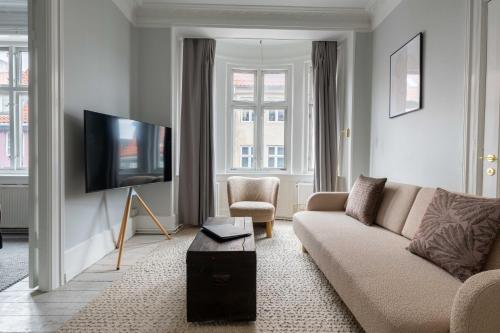 a living room with a couch and a flat screen tv at Super Central 2BR Apartment in Old Town Copenhagen in Copenhagen