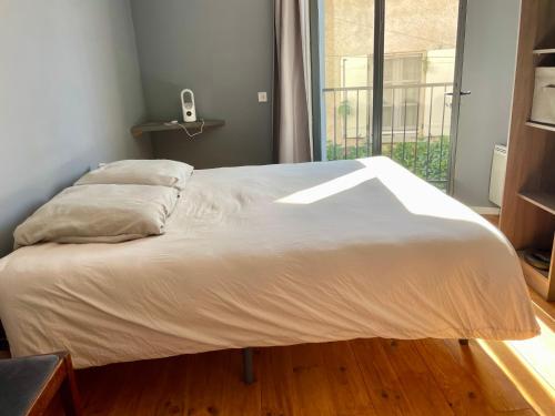 un grand lit blanc dans une chambre avec une fenêtre dans l'établissement Entre deux rivières, à Montolieu