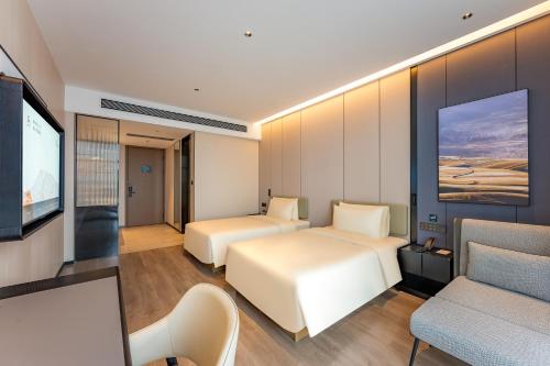 a hotel room with two beds and a flat screen tv at Atour Hotel Shaoxing Keqiao Binhai Business Center in Yüan-chia-ch'iao
