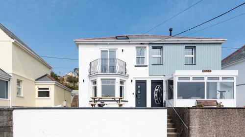 a white and blue house with a fence at HipNautic, Mevagissey, Sleeps 6 in Mevagissey