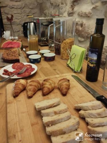 Una mesa con croissants y panes en una tabla de cortar. en Logis Hotel Restaurant L'Esquielle, en Saint-Géniès-de-Malgoirès
