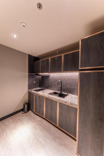 a kitchen with wooden cabinets and a sink at The All - Suite Pentacity Hotel Balikpapan in Balikpapan