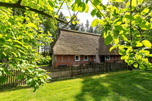 an old house with a thatched roof and a fence at Heide Ferien - Hof Bockelmann in Bispingen
