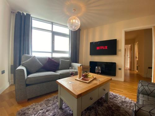 Una sala de estar con un sofá y una mesa con copas de vino. en *Modern 2 bed apartment in the heart of Cardiff*, en Cardiff