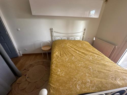 a small bedroom with a bed with a yellow bedspread at Maison avec piscine proche de Paris in Groslay