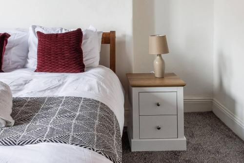 a bedroom with a bed and a night stand with a lamp at 3br Homely House For Family, Friends And Workers in Gateshead