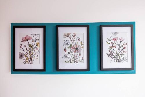 three framed drawings of flowers on a blue wall at 3br Homely House For Family, Friends And Workers in Gateshead