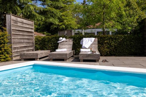 a swimming pool with two lounge chairs and a table at Tiny Lodge Basic in Harderwijk