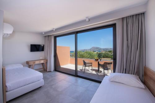 a bedroom with two beds and a balcony with a table at Kiani Beach Resort Family All Inclusive in Kalyves