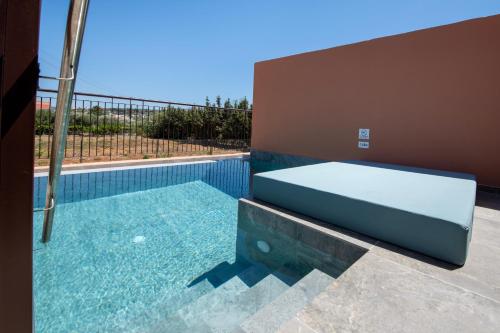 a swimming pool with a bench next to a house at Kiani Beach Resort Family All Inclusive in Kalyves