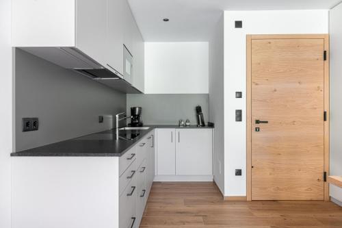 a kitchen with white cabinets and a wooden door at Apparthotel Sonnwies in Selva dei Molini