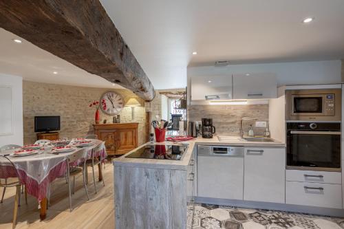 une cuisine avec une table et une cuisine avec des appareils électroménagers blancs dans l'établissement Gîte La Tourette - Charme atypique, à Jard-sur-Mer