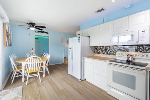 a kitchen with white appliances and a table with chairs at Charming 3BR Home with Free Parking & Game Room in Panama City