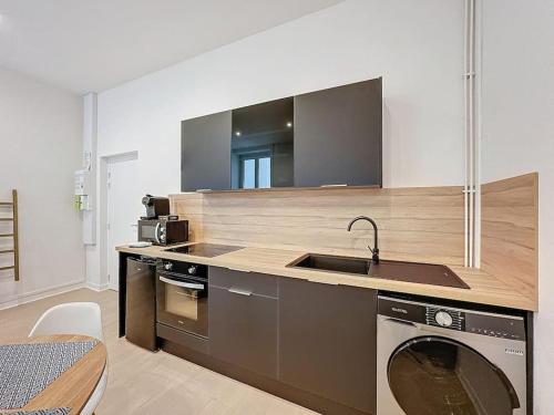 une cuisine avec un évier et une machine à laver dans l'établissement Cosy appartement, Lyon Centre Capucins 2, à Lyon