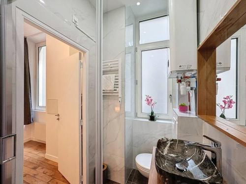 a white bathroom with a toilet and a window at Cosy appartement, Lyon Centre Capucins 2 in Lyon