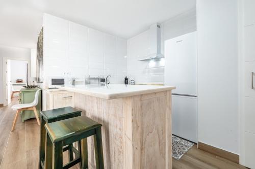 a kitchen with white cabinets and a counter with green stools at Casa Pereira in Cartaya