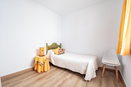 a bedroom with a bed with yellow sheets and a chair at Casa Pereira in Cartaya