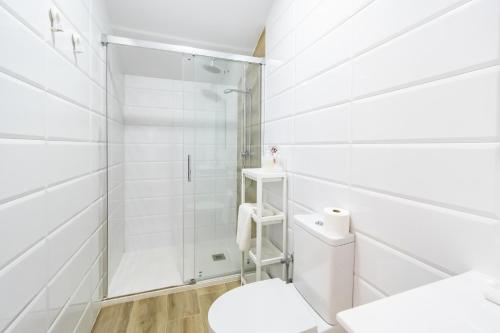 a white bathroom with a shower and a toilet at Casa Pereira in Cartaya