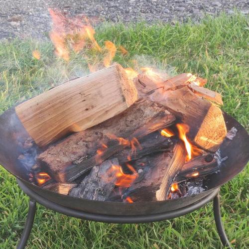 a fire pit with a bunch of wood on it at American School Bus Glamping with Hot Tub in Woolacombe! in Lee