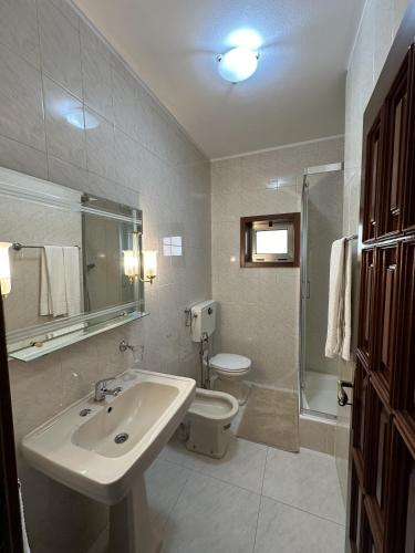 a white bathroom with a sink and a toilet at Quinta da Touça in Baião