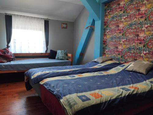 a bedroom with two beds and a wall with a mural at Green Hous agroturystyka in Pelnik
