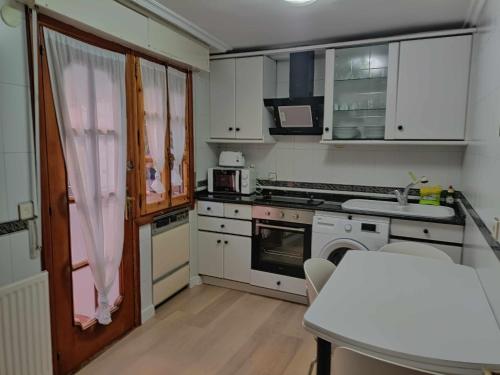a small kitchen with white cabinets and a table at El mirador del río de Arnedillo in Arnedillo