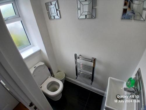 baño con aseo, ventana y lavamanos en Hornchurch House - Romford, en Harold Wood