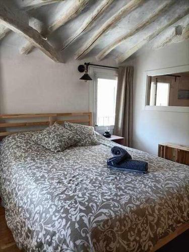 a bedroom with a bed with a comforter and a window at El mirador del río de Arnedillo in Arnedillo