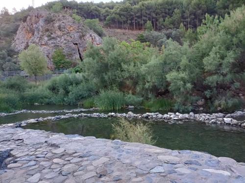 a river with rocks and trees and a mountain at El mirador del río de Arnedillo in Arnedillo