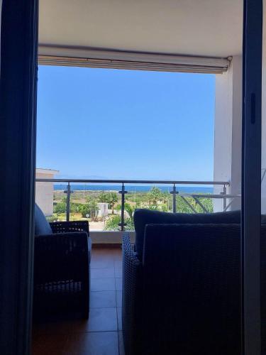 a room with two chairs and a large window with a view at Appartement à Bahia golf Beach Bouznika in Kasba Bou Hamira