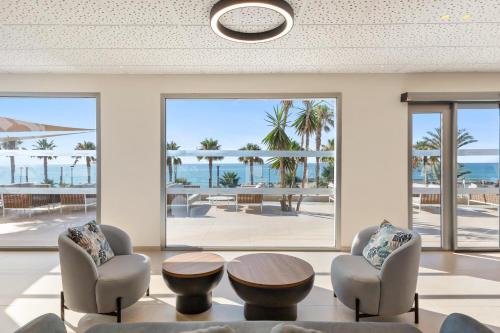 a living room with chairs and a table and a view of the ocean at Best Club Vacaciones Pueblo Indalo in Mojácar