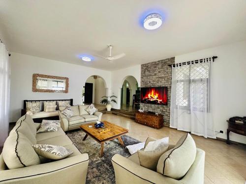 a living room with two couches and a fireplace at Jasmin Villa in Mtwapa