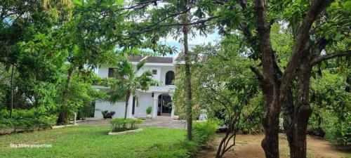 a white house with trees in front of it at Jasmin Villa in Mtwapa