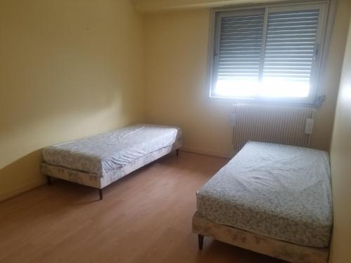 due letti singoli in una stanza con finestra di Studio Metro GALLIENI a Bagnolet