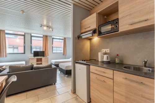 a kitchen and a living room with a couch at Condo Gardens Brussels in Brussels