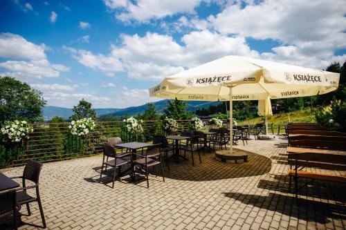 a patio with tables and chairs and an umbrella at Hotel Dziki Potok Karpacz Konferencje & SPA in Karpacz